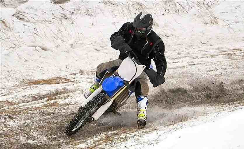 The rider controls his balance on the icy and snowy road surface